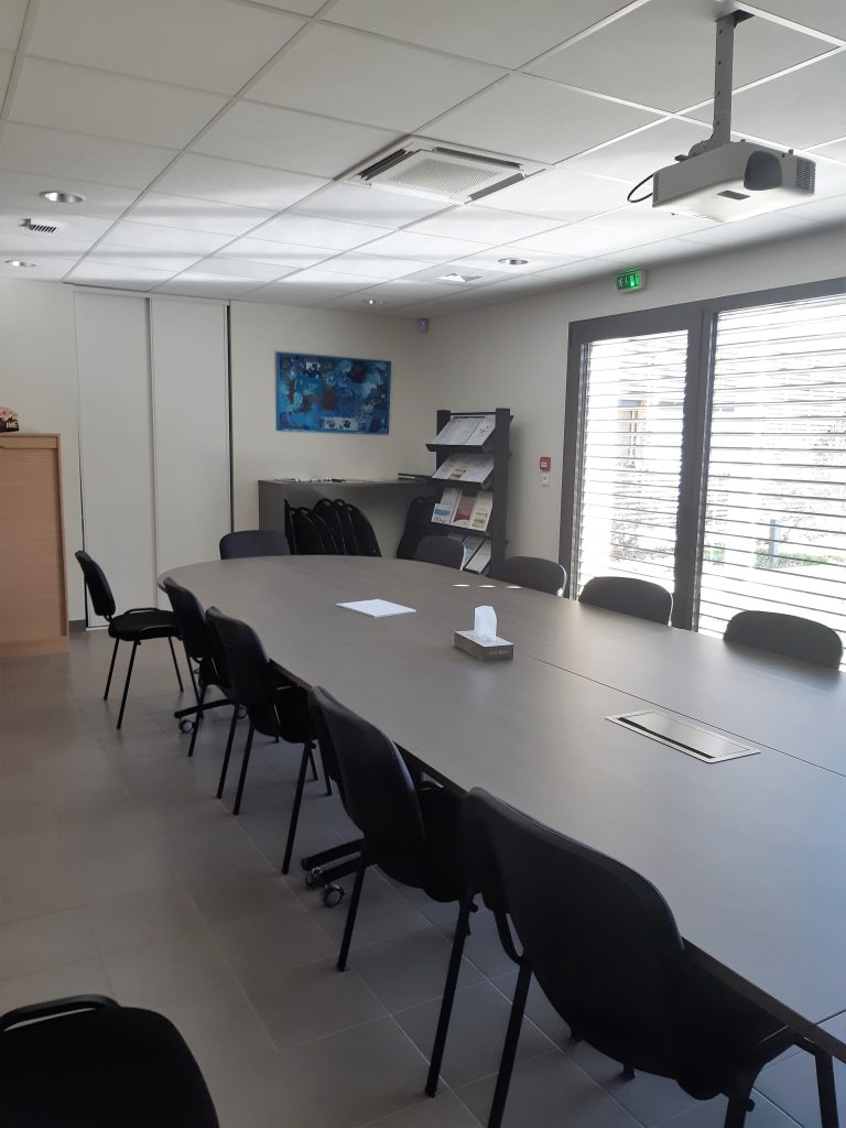 Salle de réunion avec une grande table centrale et dix chaises