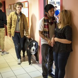 Jeunes étudiants dans le couloir de l'IFMK DV en train de discuter. Au second plan, Marc, non voyant depuis l'âge de 6 ans, avec son chien guide.
