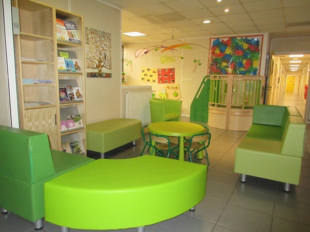 Salon d'accueil avec fauteuils verts pomme et bibliothèque